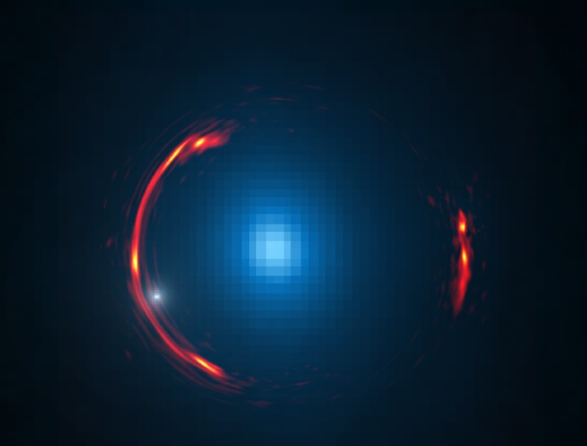 Composite image of the gravitational lens SDP.81 showing the distorted image of the more distant galaxy (red arcs) and the nearby lensing galaxy (blue center object). By analyzing the distortions in the ring, astronomers have determined that a dark dwarf galaxy (data indicated by white dot near left lower arc segment) is lurking nearly 4 billion light-years away. (Image: Y. Hezaveh, Stanford Univ.; ALMA (NRAO/ESO/NAOJ); NASA/ESA Hubble Space Telescope))